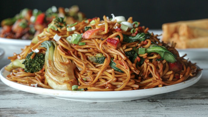 Plate of wide rice noodles stir-fried with vegetables